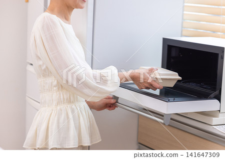 Meals: Senior women warming up their packed lunches at home. Meals: Senior women warming up their packed lunches at home. 141647309