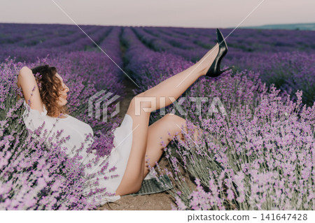 Lavender woman high-heels field resting in a beautiful purple flower meadow during a serene sunny summer afternoon outdoors vacation lifestyle Lavender woman high-heels field resting in a beautiful purple flower meadow during a serene sunny summer afternoon outdoors vacation lifestyle 141647428
