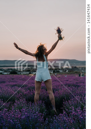 Lavender, woman, summer, woman standing in blooming field with arms raised holding lavender bouquet during golden sunset in summer nature landscape Lavender, woman, summer, woman standing in blooming field with arms raised holding lavender bouquet during golden sunset in summer nature landscape 141647434