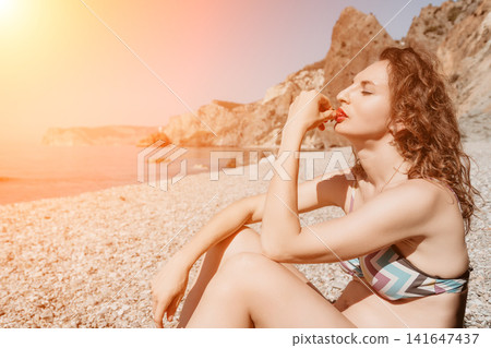 Woman strawberry beach, young female eating fresh fruit relaxing on pebble shore during golden hour vacation at tropical seaside resort Woman strawberry beach, young female eating fresh fruit relaxing on pebble shore during golden hour vacation at tropical seaside resort 141647437