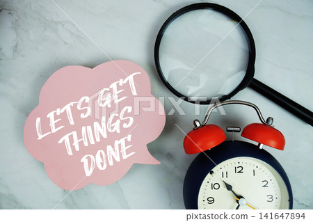 Let's Get Things Done text with magnifying glass and alarm clock on marble background Let's Get Things Done text with magnifying glass and alarm clock on marble background 141647894