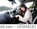 A young Asian woman operating the car's navigation system inside the car. 141648181