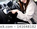 A young Asian woman operating the car's navigation system inside the car. 141648182