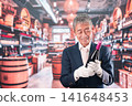 A middle-aged male sommelier holding a bottle of wine 141648453