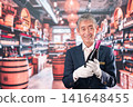 A middle-aged male sommelier holding a bottle of wine 141648455