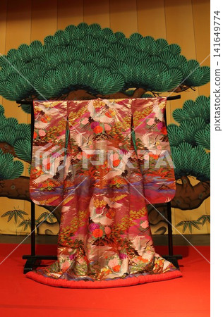A gorgeous uchikake (wedding kimono) displayed against a backdrop of pine trees. A gorgeous uchikake (wedding kimono) displayed against a backdrop of pine trees. 141649774