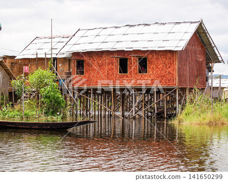 Traditional stilt houses at Inle Lake, Myanmar, showing floating village lifestyle, sustainable local living and wooden homes above calm water in Shan State 141650299