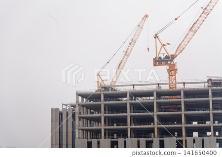 Crane Lifting Building Materials on Tall Skyscraper Construction Site Crane Lifting Building Materials on Tall Skyscraper Construction Site 141650400