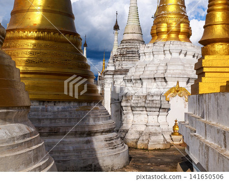 Golden Buddhist pagodas at Inle Lake, Myanmar, symbol of spiritual travel and cultural immersion, ancient stupas glowing in afternoon light under dramatic sky in Shan State Golden Buddhist pagodas at Inle Lake, Myanmar, symbol of spiritual travel and cultural immersion, ancient stupas glowing in afternoon light under dramatic sky in Shan State 141650506