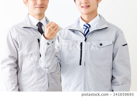 A young man and a middle-aged man in work clothes making a victory pose. A young man and a middle-aged man in work clothes making a victory pose. 141650693