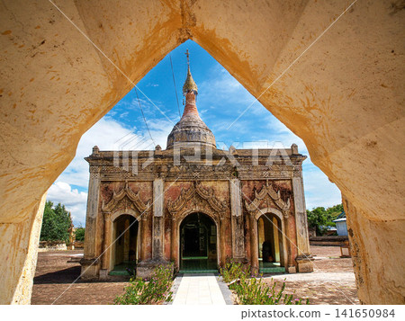 Hsu Taung Pyi Pagoda framed by an old brick arch in the Bagan archaeological zone in Myanmar, ancient Buddhist temple rising above the temple plain under a soft blue sky and evening light Hsu Taung Pyi Pagoda framed by an old brick arch in the Bagan archaeological zone in Myanmar, ancient Buddhist temple rising above the temple plain under a soft blue sky and evening light 141650984