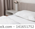 Modern cozy bedroom with white bedding and bedside table 141651752