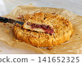 Homemade cherry crumb cake with golden streusel topping on parchment paper with one slice raised on a knife Homemade cherry crumb cake with golden streusel topping on parchment paper with one slice raised on a knife 141652325