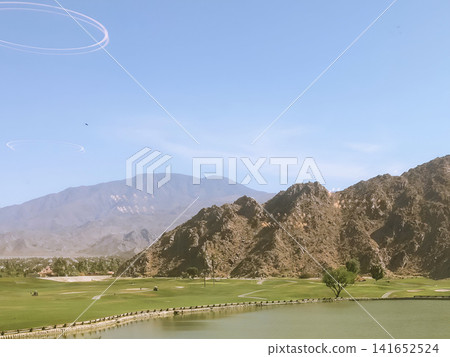 A breathtaking view of La Quinta's golf course and rocky hills against a clear blue sky. A breathtaking view of La Quinta's golf course and rocky hills against a clear blue sky. 141652524