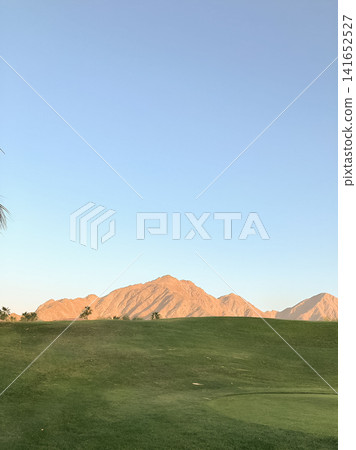 The scenery of La Quinta's golf course and the majestic mountain range bathed in the setting sun. The scenery of La Quinta's golf course and the majestic mountain range bathed in the setting sun. 141652527