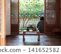 A woman sitting on the veranda of a traditional Korean house, a "hanok." 141652582