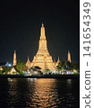 The Wat Arun stupa at night, its lights reflecting on the surface of the Chao Phraya River. 141654349