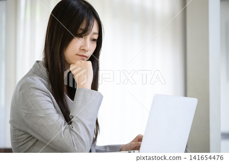 一位日本女性正在筆記型電腦前思考 一位日本女性正在筆記型電腦前思考 141654476