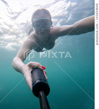 Snorkeling selfie captures young woman swimming underwater with goggles in turquoise sea Snorkeling selfie captures young woman swimming underwater with goggles in turquoise sea 141654648