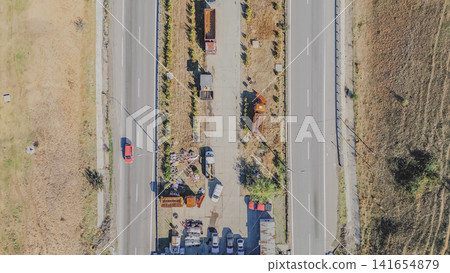 Top down aerial view of dual carriageway highway with central service maintenance yard and parked trucks in Greece for road transportation stock photo background Top down aerial view of dual carriageway highway with central service maintenance yard and parked trucks in Greece for road transportation stock photo background 141654879