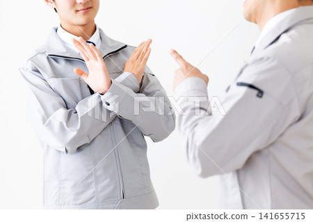 A young man in work clothes who doesn't want to be scolded and a middle-aged man scolding his subordinate. A young man in work clothes who doesn't want to be scolded and a middle-aged man scolding his subordinate. 141655715