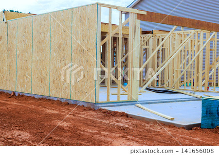Builders are working on placing wooden beams frames for structure on site with some materials around. Builders are working on placing wooden beams frames for structure on site with some materials around. 141656008