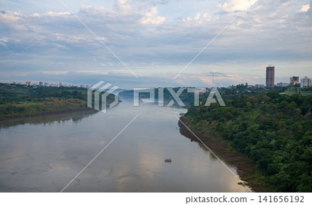 Under a calm evening sky, the Paraná River separates Brazil and Paraguay. Under a calm evening sky, the Paraná River separates Brazil and Paraguay. 141656192