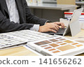 An interior designer's hands inputting information into a tablet while looking at building material samples. 141656262