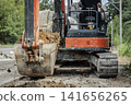 A construction site showing a hydraulic excavator scooping up soil and an operator. 141656265