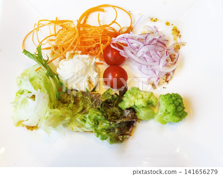A vibrant arrangement of fresh mixed salad on a square white plate. A vibrant arrangement of fresh mixed salad on a square white plate. 141656279
