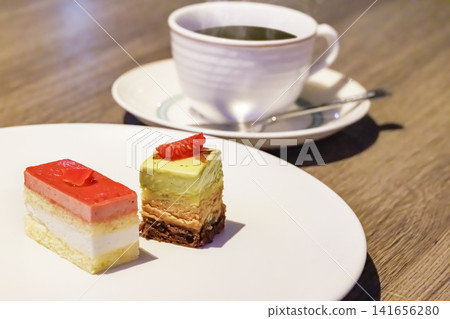 A warm hot coffee and a dessert plate visible in the background. A warm hot coffee and a dessert plate visible in the background. 141656280