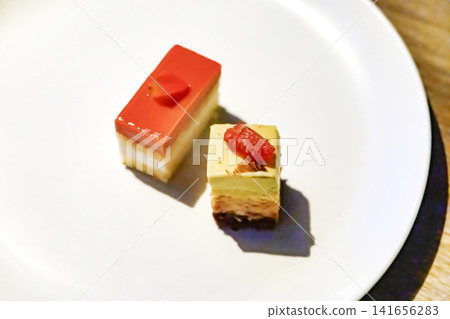 Two kinds of mini cakes elegantly arranged on a white plate. Two kinds of mini cakes elegantly arranged on a white plate. 141656283