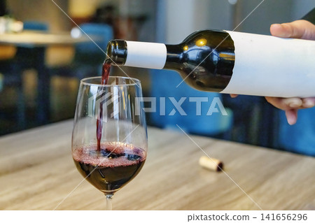 The red wine being poured into the glass and its beautiful, flowing lines. The red wine being poured into the glass and its beautiful, flowing lines. 141656296
