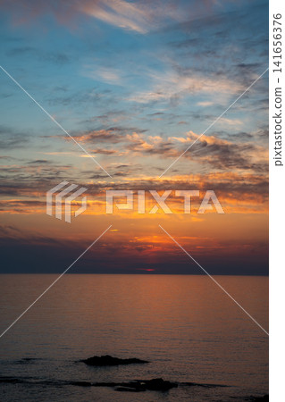 橘色的夕陽雲彩和橘色的海面倒影。 橘色的夕陽雲彩和橘色的海面倒影。 141656376