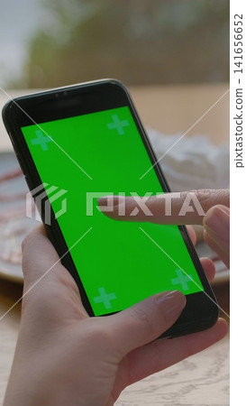 Vertical video. Businesswoman using mobile cell phone with green touch screen in cafe. Green Screen. Vertical video. Businesswoman using mobile cell phone with green touch screen in cafe. Green Screen. 141656652