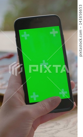 Vertical video. Businesswoman using mobile cell phone with green touch screen in cafe. Green Screen. Vertical video. Businesswoman using mobile cell phone with green touch screen in cafe. Green Screen. 141656653