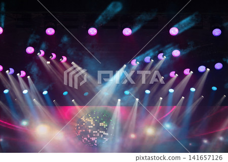 Vibrant light display with colorful beams and a disco ball during a lively night event in an indoor venue Vibrant light display with colorful beams and a disco ball during a lively night event in an indoor venue 141657126