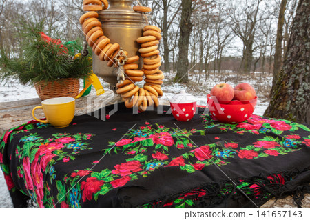 Decorative table setup in the woods with traditional items and snacks during winter Decorative table setup in the woods with traditional items and snacks during winter 141657143