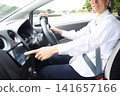 A young Asian man operating the car's navigation system inside the car. 141657166