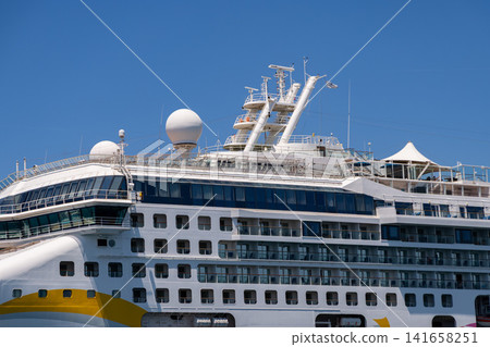 Modern cruise ship with multiple decks and balconies against a clear blue sky 141658251