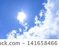 Summer sky in early August: Sun and white clouds against a blue sky background. 141658466