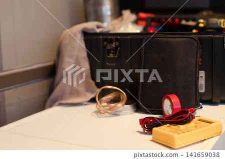 Essential electrical tools including a multimete ,copper wire,red electrical tape and a dark toolbox on a white surface symbolizing diligent work. Labor day. Copy space Essential electrical tools including a multimete ,copper wire,red electrical tape and a dark toolbox on a white surface symbolizing diligent work. Labor day. Copy space 141659038