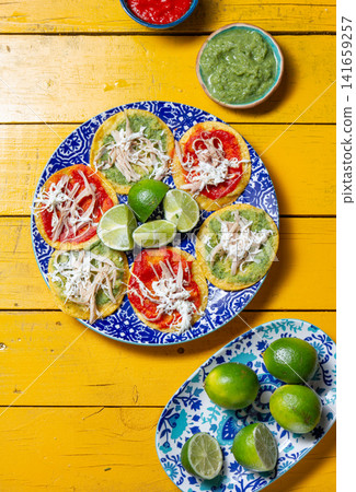 Delicious Mexican chalupas topped with chicken, served on colorful ceramics Delicious Mexican chalupas topped with chicken, served on colorful ceramics 141659257