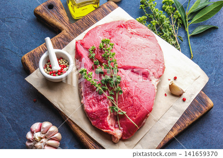 Raw Beef Steak on Wooden Cutting Board with Herbs and Spices 141659370