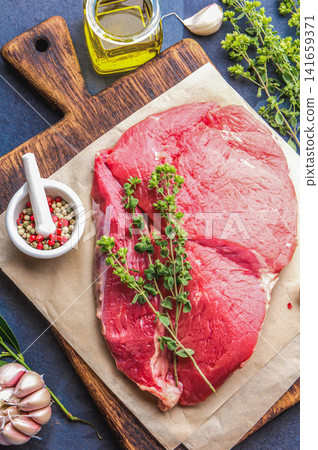 Raw Beef Steak on Wooden Cutting Board with Herbs and Spices Raw Beef Steak on Wooden Cutting Board with Herbs and Spices 141659371