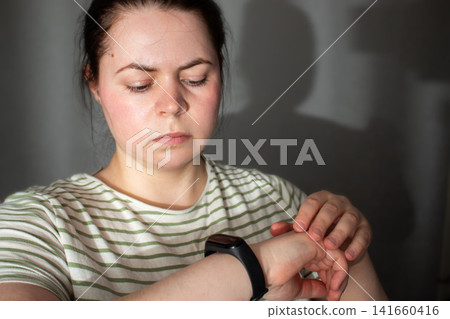 Woman checks health rhythm and pulse then puts watch to sleep. No obsession about data checking. Moving from rigid self-tracking to intuitive balanced tech use Woman checks health rhythm and pulse then puts watch to sleep. No obsession about data checking. Moving from rigid self-tracking to intuitive balanced tech use 141660416