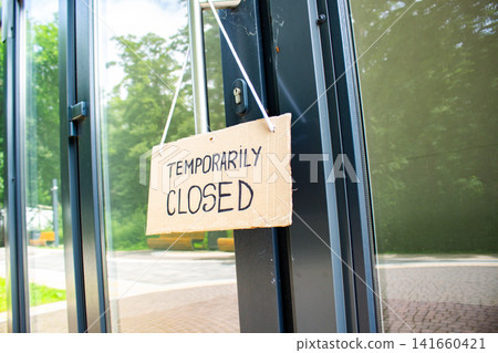 TEMPORARILY CLOSED sign hanging on small shop door. Small business shutting down due to financial crisis. Local business unable to survive economic pressure TEMPORARILY CLOSED sign hanging on small shop door. Small business shutting down due to financial crisis. Local business unable to survive economic pressure 141660421