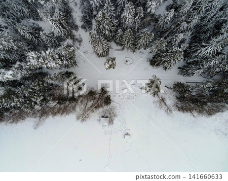 Aerial winter clearing with firepit and huts in boreal forest Aerial winter clearing with firepit and huts in boreal forest 141660633