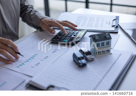 Businessman reviewing financial documents for property investment and auto finance. Businessman reviewing financial documents for property investment and auto finance. 141660716