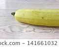 Whole pale green zucchini on light wooden table. Minimal composition. Selective focus Whole pale green zucchini on light wooden table. Minimal composition. Selective focus 141661032